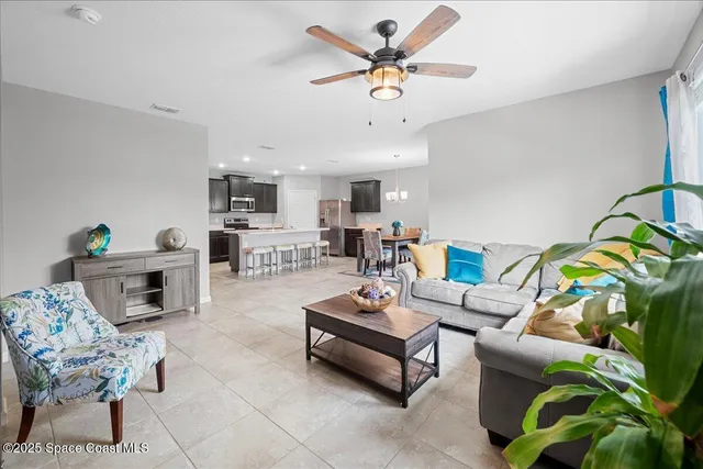 a living room with furniture kitchen view and a chandelier