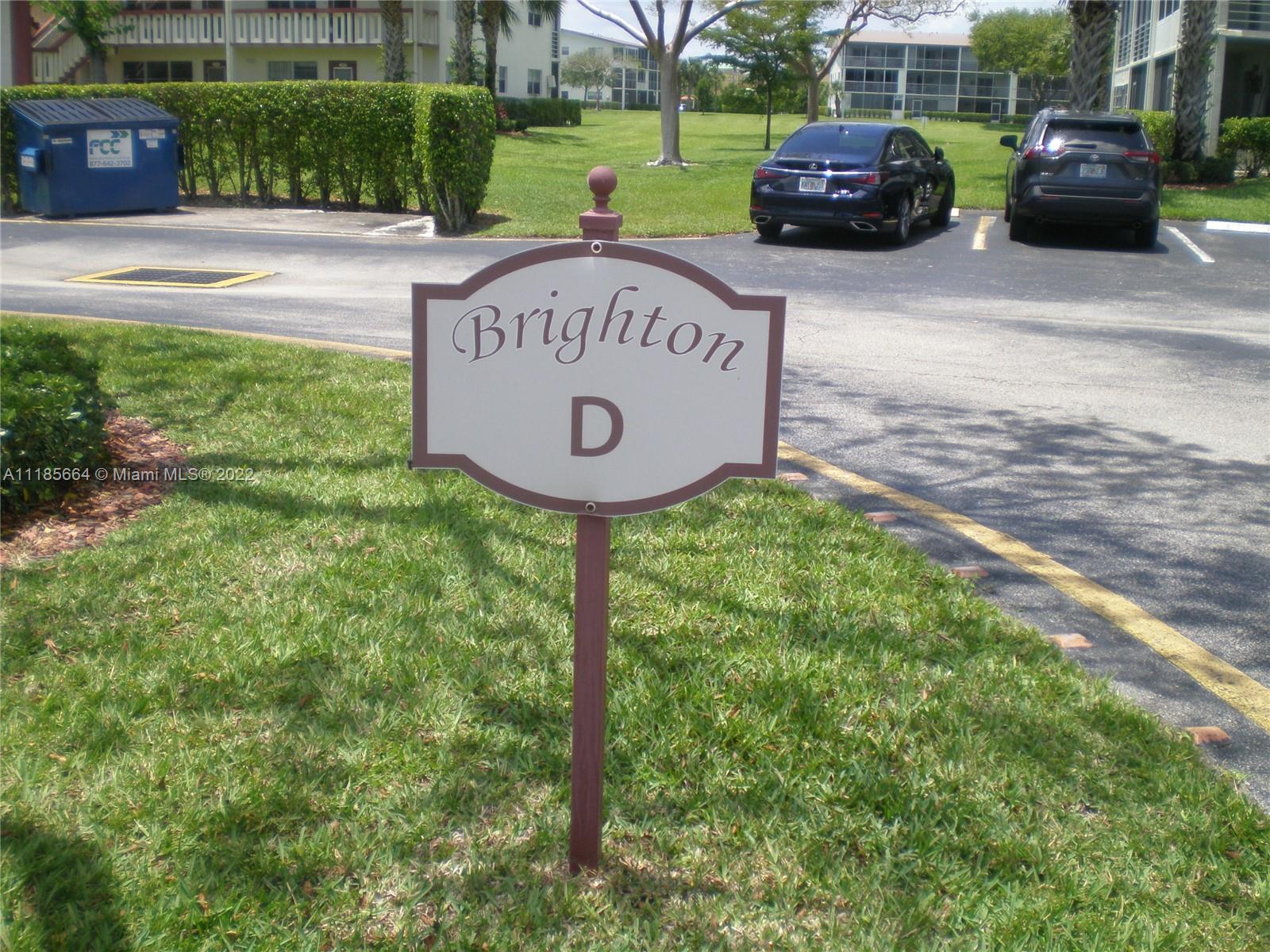 129 Brighton D, Unit 129 Boca Raton, FL 33434 - Photo 22 of 28 a view of a sign board with a car park in the back