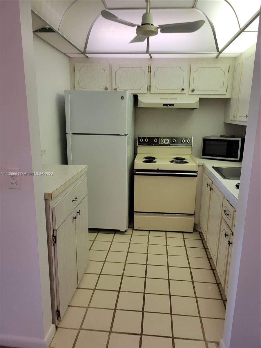 129 Brighton D, Unit 129 Boca Raton, FL 33434 - Photo 5 of 28 a kitchen with white cabinets a stove top oven and white stainless steel appliances