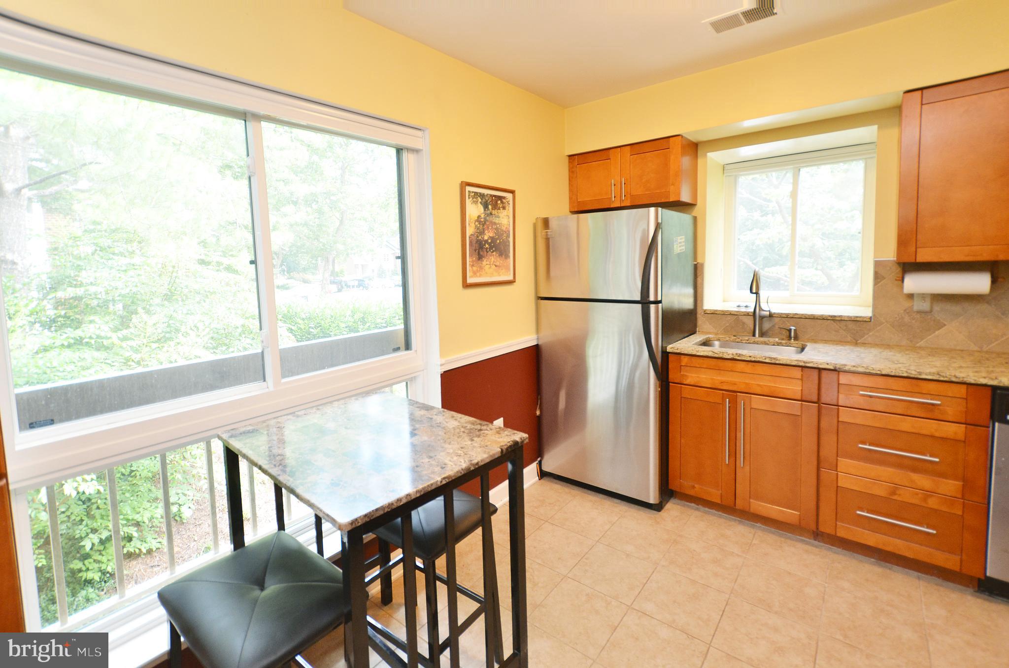 11214 Beaver Trail Court, Unit 12 Reston, VA 20191 - Photo 3 of 27 a kitchen with stainless steel appliances granite countertop a stove a refrigerator a dining table and chairs with wooden floor