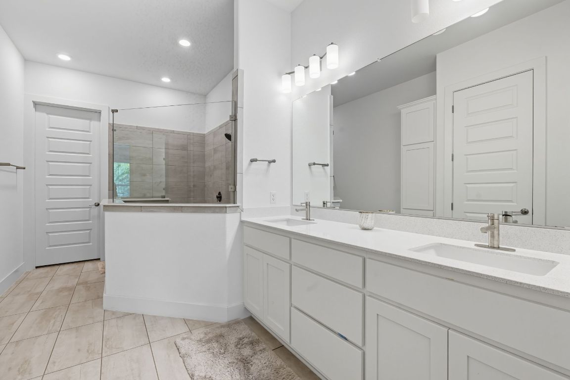 101 Cartwheel Bend, Unit 52 Austin, TX 78738 - Photo 18 of 31 a bathroom with a double vanity sink a mirror and a shower