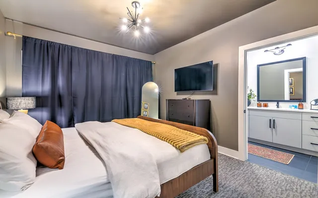 a bedroom with a large bed and a flat tv screen on dresser