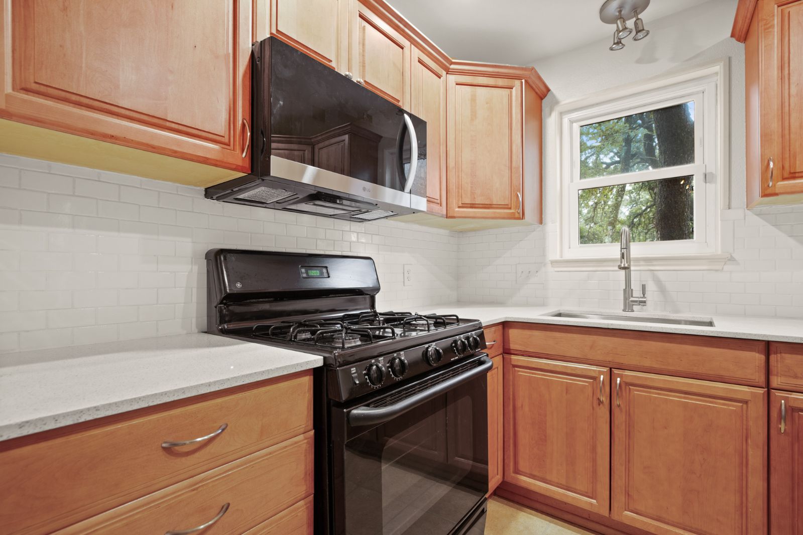 11970 Jollyville Road, Unit 216 Austin, TX 78759 - Photo 11 of 20 Kitchen with black gas stove, stainless steel microwave, light stone countertops, and backsplash