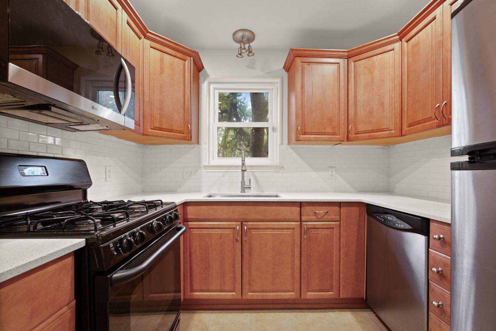 11970 Jollyville Road, Unit 216 Austin, TX 78759 - Photo 12 of 20 Kitchen with stainless steel appliances, decorative backsplash, wood finish cabinets, and light stone countertops
