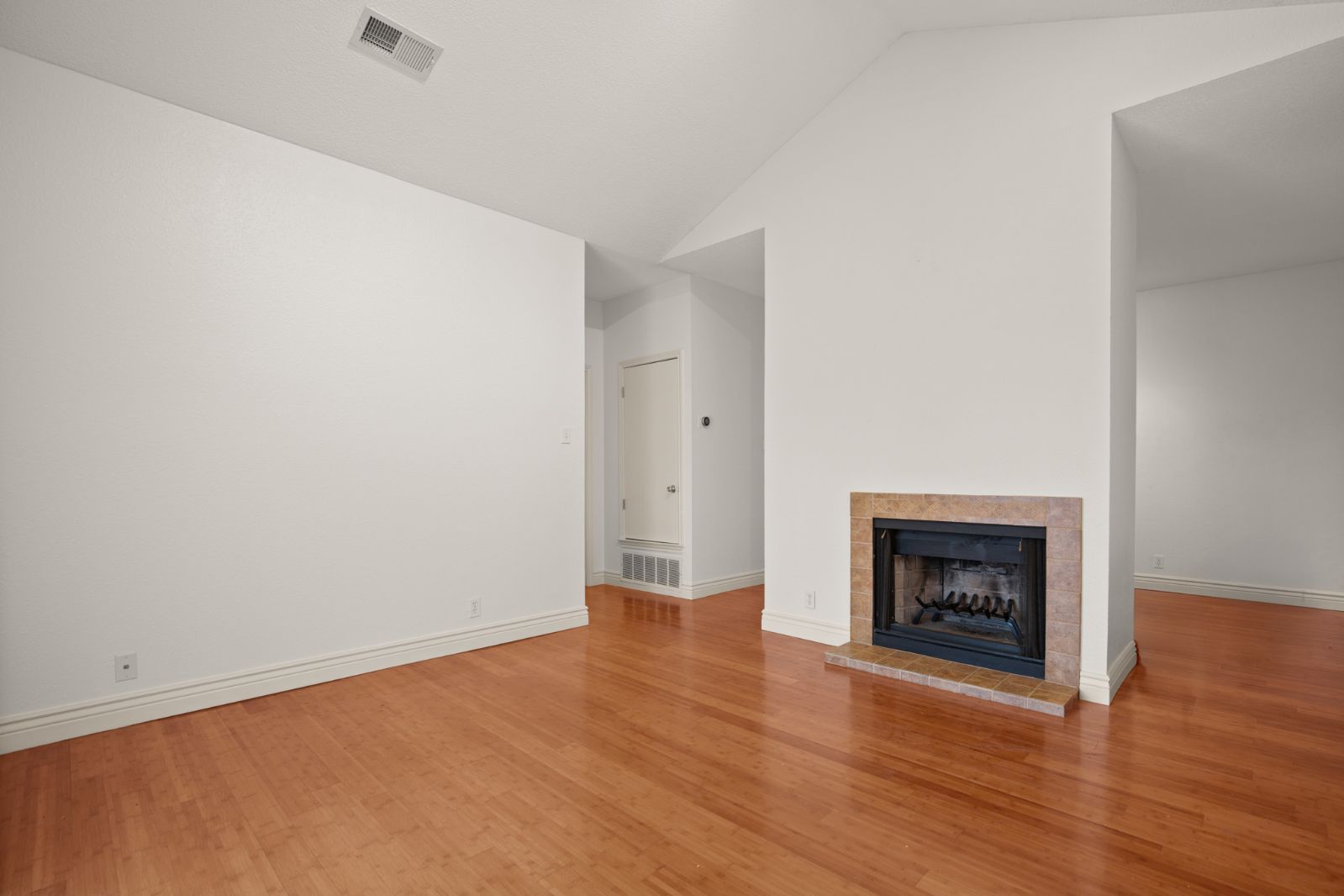 11970 Jollyville Road, Unit 216 Austin, TX 78759 - Photo 5 of 20 Unfurnished living room featuring lofted ceiling, a fireplace with raised hearth, and light wood finished floors