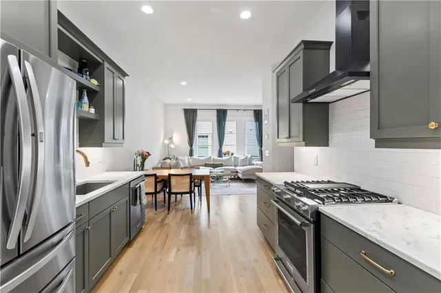 a kitchen with stainless steel appliances granite countertop a stove top oven a sink dishwasher a dining table and chairs with wooden floor