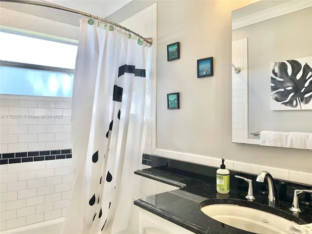 a bathroom with a granite countertop sink a mirror and shower
