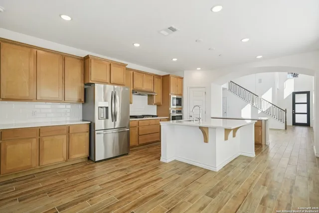 a kitchen with stainless steel appliances kitchen island wooden floors and white cabinets