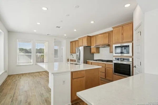 a large kitchen with stainless steel appliances a large counter top a stove a refrigerator cabinets and a sink