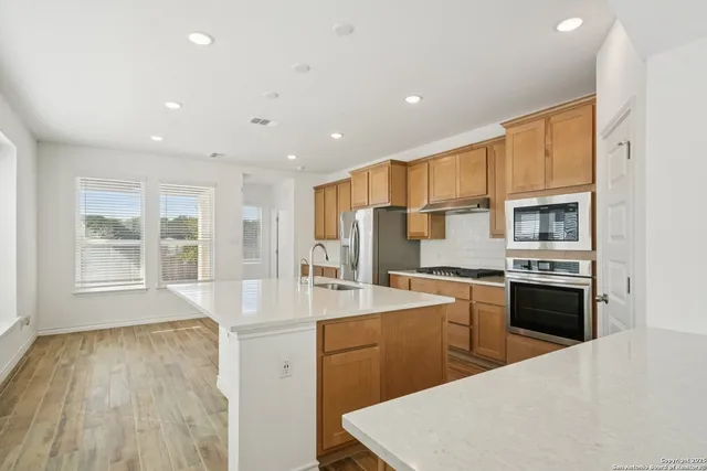 a large kitchen with stainless steel appliances a large counter top a stove a refrigerator cabinets and a sink