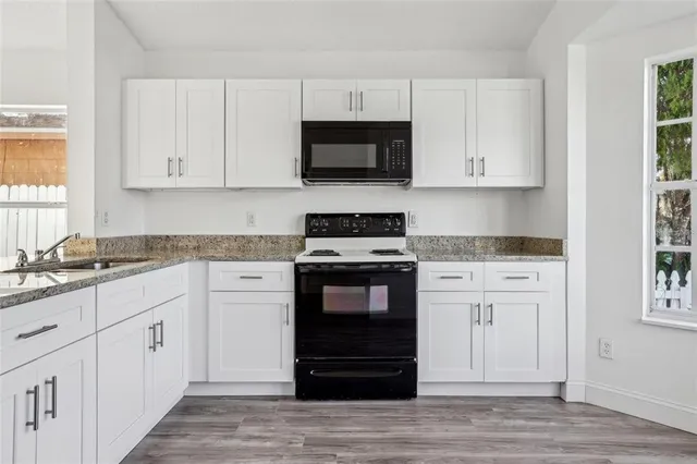 a kitchen with granite countertop white cabinets and stainless steel appliances