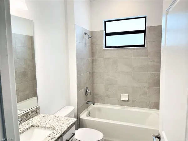 a bathroom with a granite countertop bathtub shower and toilet