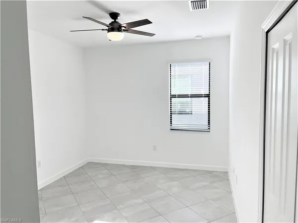 an empty room with a ceiling fan and a window