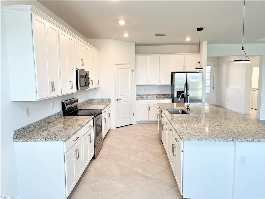 11163 Canopy Loop Fort Myers, FL 33913 - Photo 4 of 16 Kitchen with stainless steel appliances, light stone countertops, white cabinets, hanging light fixtures, and an island with sink