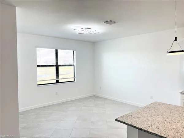 an empty room with a chandelier fan and windows