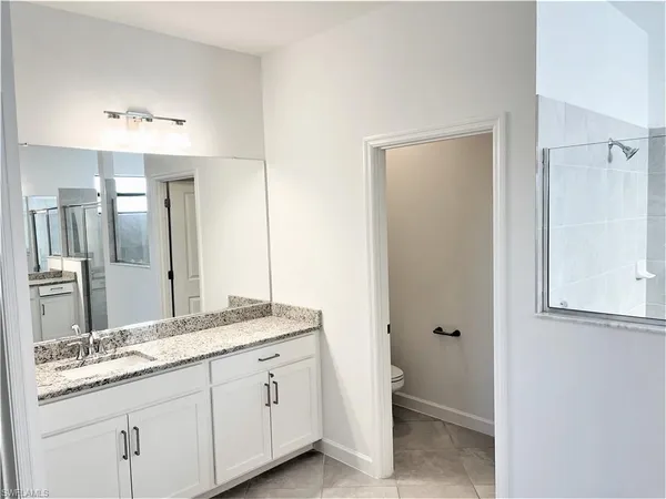 a bathroom with a granite countertop sink a toilet and a mirror