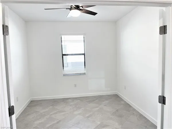 an empty room with windows and fan