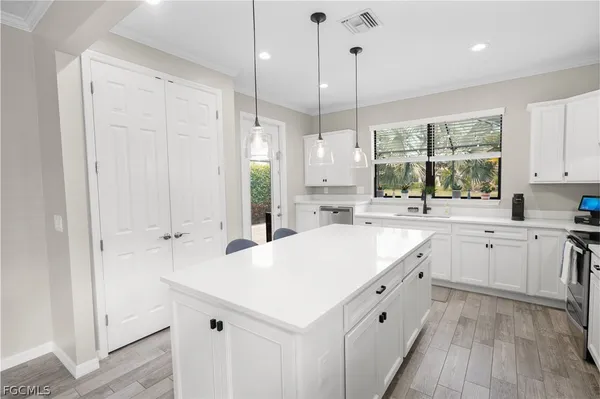 a large white kitchen with a large window a sink stainless steel appliances and cabinets
