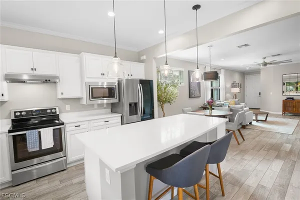 a kitchen with stainless steel appliances a stove a sink a refrigerator a fireplace and white cabinets