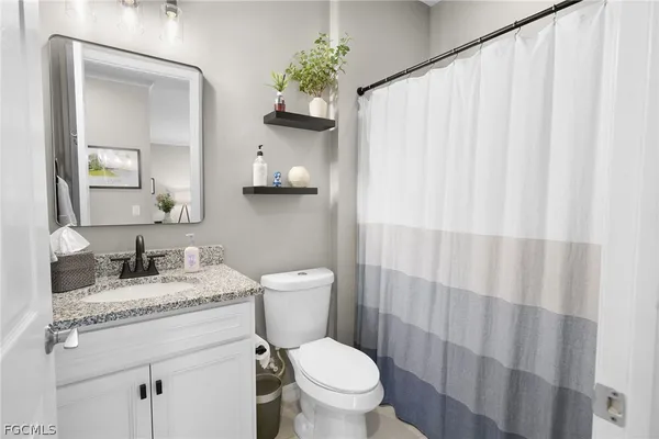 a bathroom with a granite countertop sink toilet and mirror