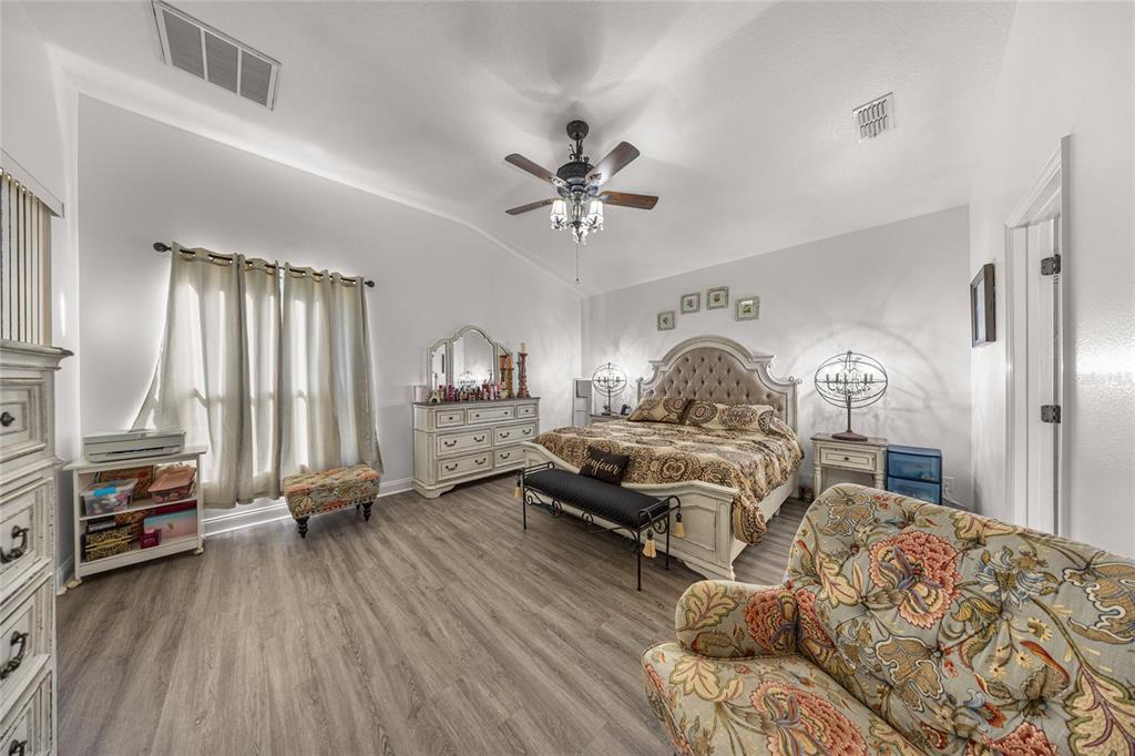 4590 Southwest 111th Place Ocala, FL 34476 - Photo 20 of 36 a spacious bedroom with a bed and a chandelier