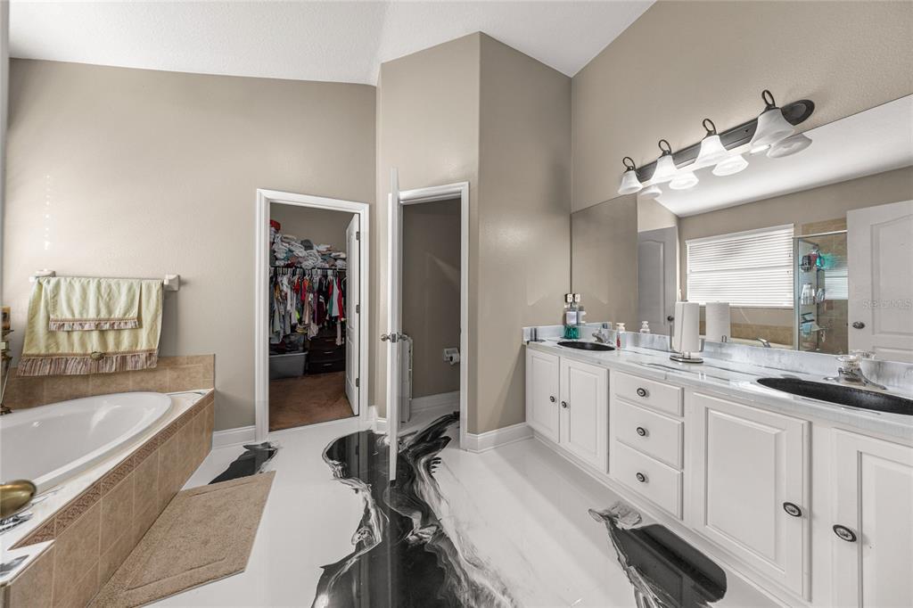 4590 Southwest 111th Place Ocala, FL 34476 - Photo 22 of 36 a spacious bathroom with a granite countertop sink mirror and a bathtub