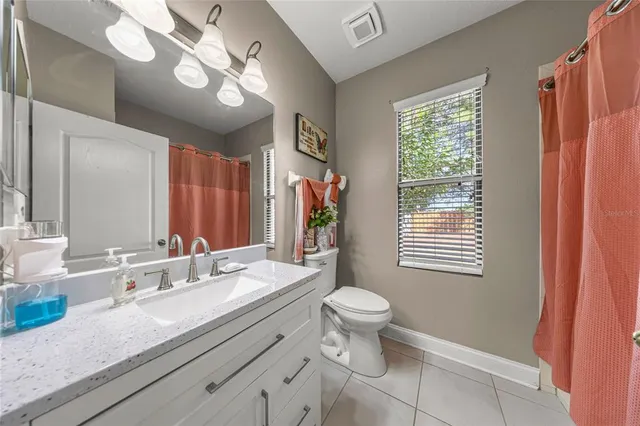 a bathroom with a granite countertop sink a toilet a mirror a vanity and window
