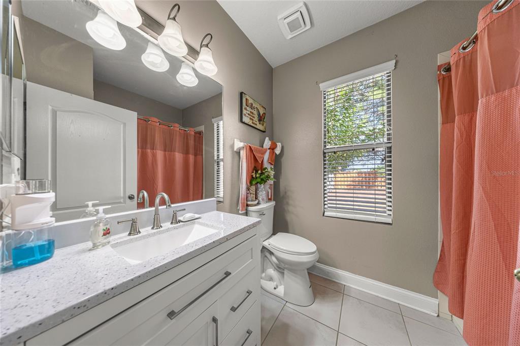 4590 Southwest 111th Place Ocala, FL 34476 - Photo 26 of 36 a bathroom with a granite countertop sink a toilet a mirror a vanity and window