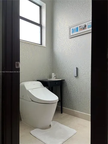 a white toilet sitting in a bathroom next to a window