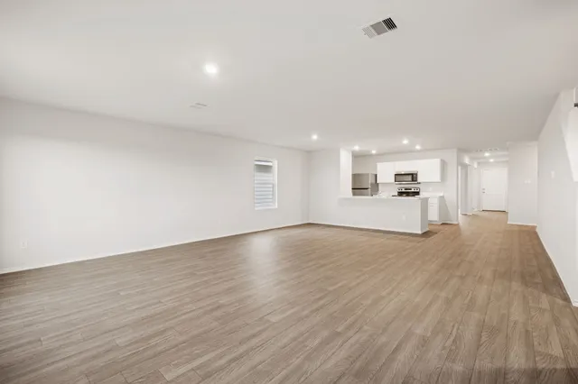 a view of an empty room and a kitchen