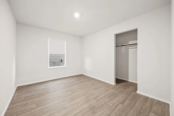 an empty room with wooden floor closet and windows