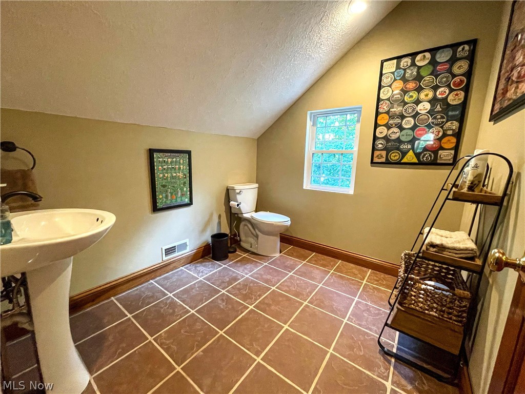 2002 Laurel Ridge Road Culloden, WV 25510 - Photo 25 of 36 Half Bathroom featuring tile patterned flooring, vaulted ceiling, toilet, and a textured ceiling