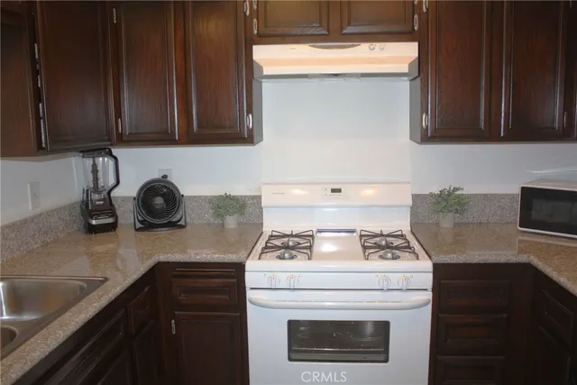 a kitchen with granite countertop a sink a stove and cabinets