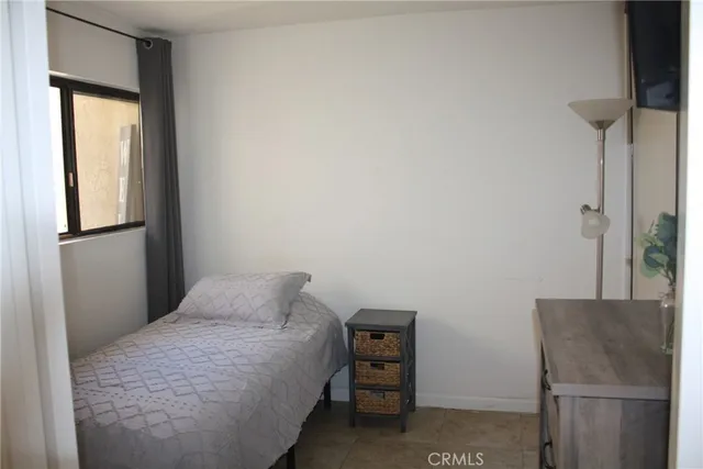 a bedroom with a bed and a refrigerator