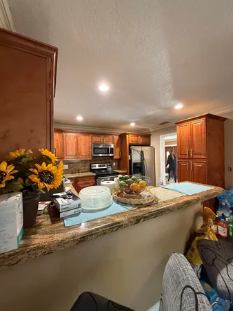 a view of a kitchen with kitchen island a large counter top space a sink stainless steel appliances and cabinets