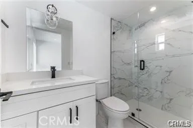 a bathroom with a granite countertop sink a toilet and shower