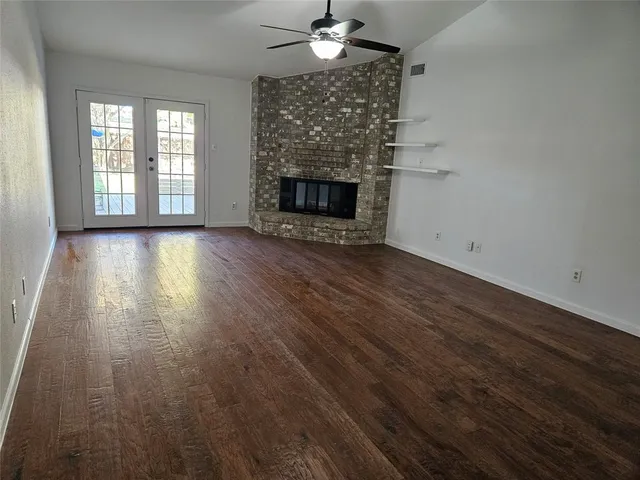 an empty room with wooden floor fireplace and windows