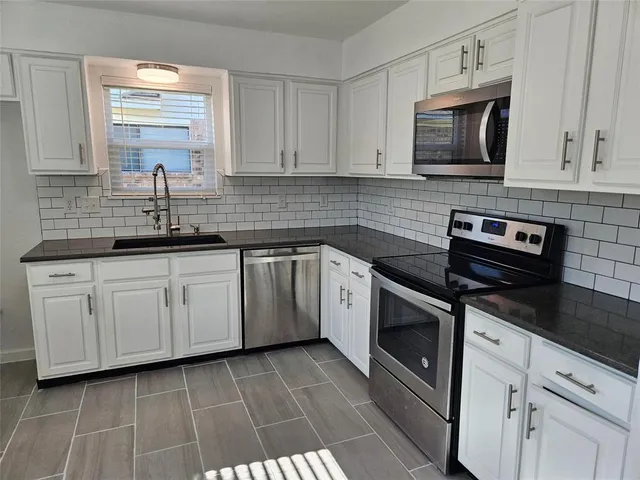 a kitchen with cabinets stainless steel appliances and sink