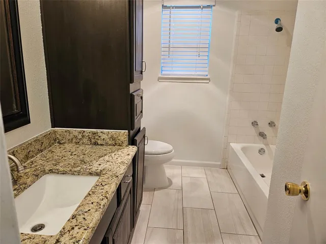 a bathroom with a granite countertop sink a toilet and shower