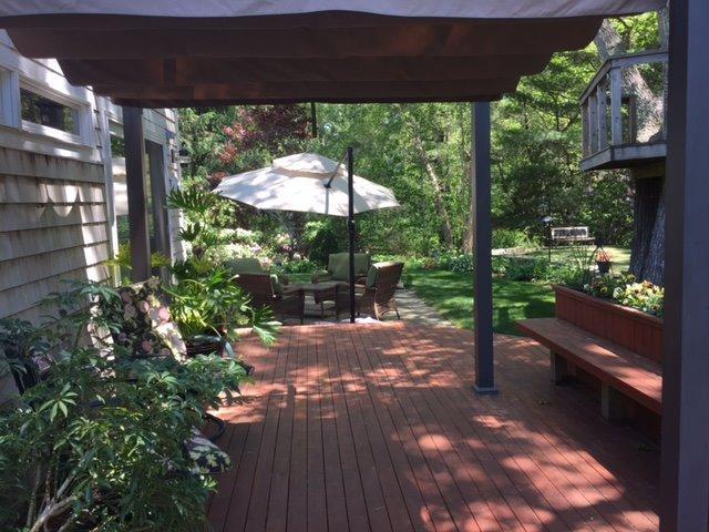43 Poponessett Road Cotuit, MA 02635 - Photo 26 of 31 a view of a patio with table and chairs under an umbrella