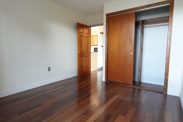 an empty room with wooden floor and closet