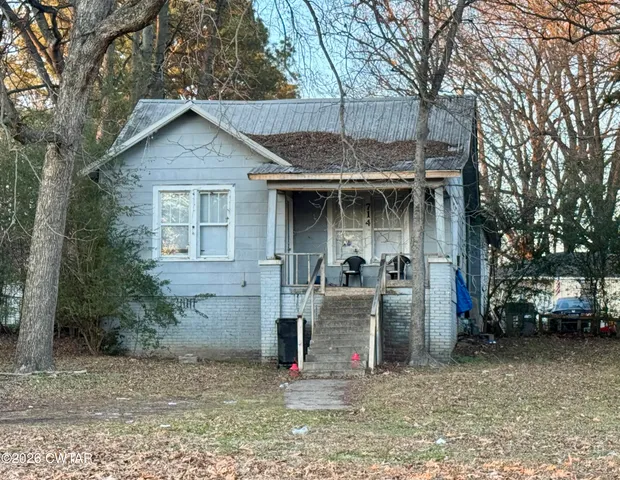 a view of a house with large trees and barbeque oven