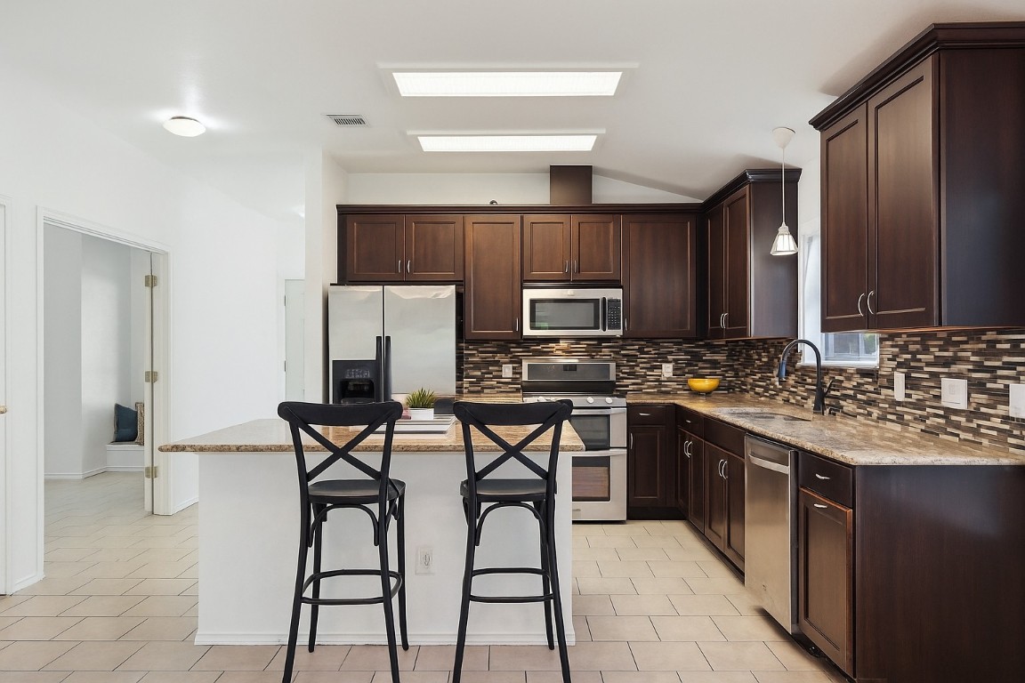 1600 Thibodeaux Drive Round Rock, TX 78664 - Photo 1 of 1 a kitchen with stainless steel appliances granite countertop a stove top oven a sink dishwasher and a refrigerator with wooden cabinets