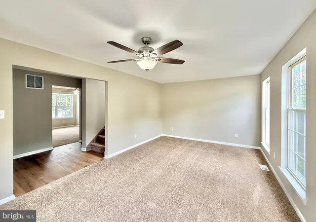an empty room with windows and fan