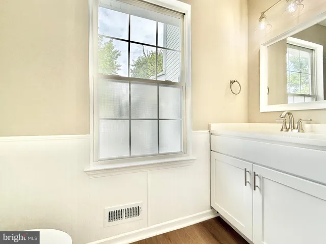 a bathroom with a granite countertop toilet a sink and a window