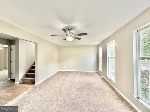 an empty room with wooden floor cabinet and windows
