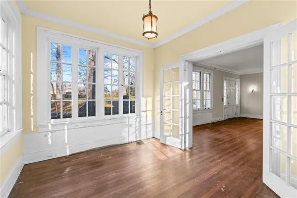 a view of an empty room with wooden floor and a window