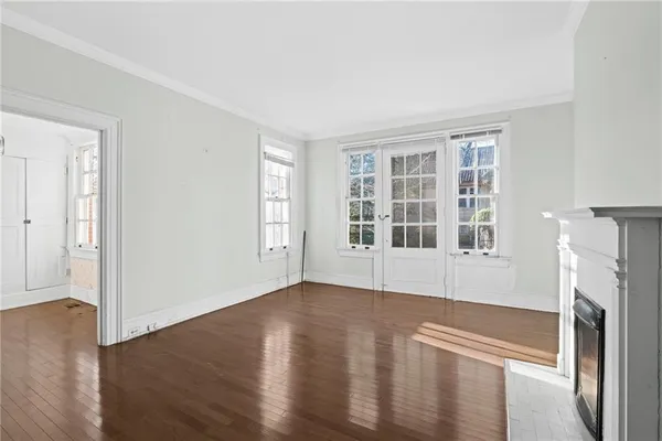 an empty room with wooden floor fireplace and windows
