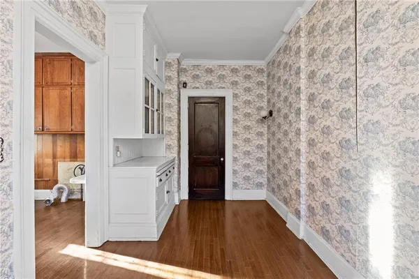 a view of an empty room with wooden floor and closet