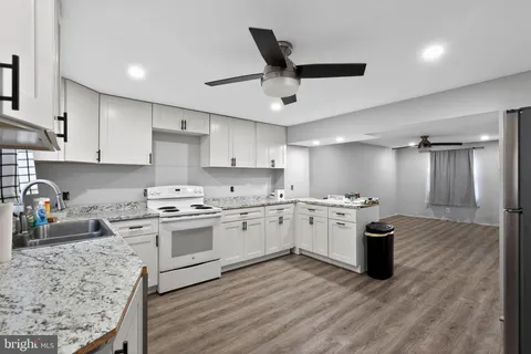 a kitchen with a stove sink cabinets and wooden floor